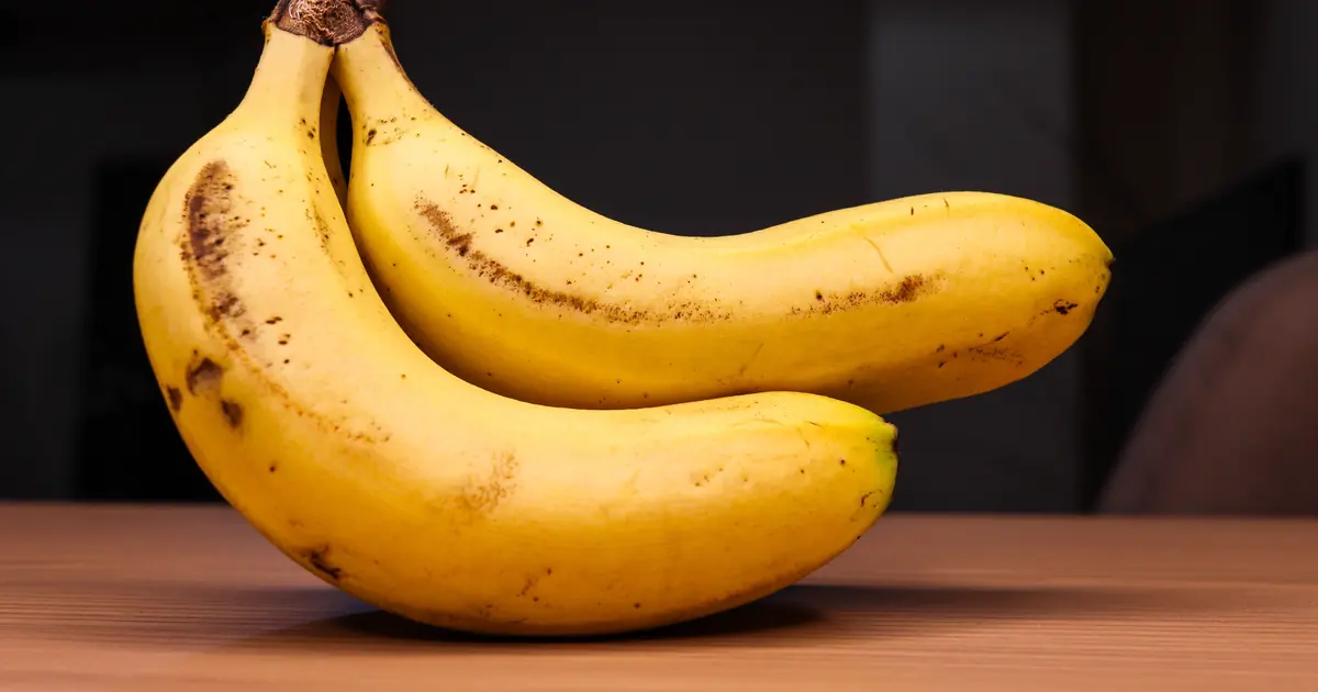 Curious cat sniffing a ripe banana on a kitchen counter